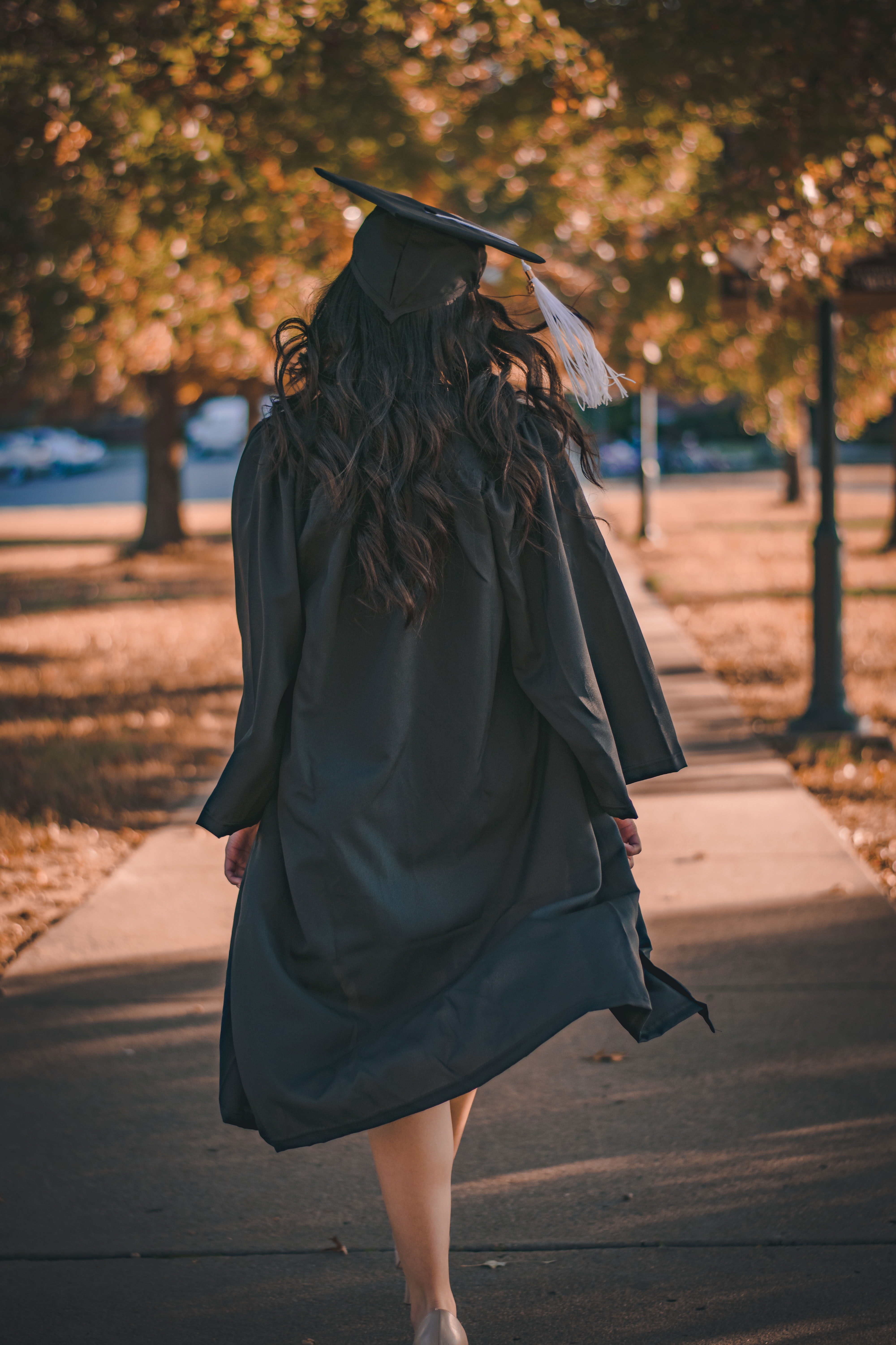 woman in graduation regalia with back facing camera